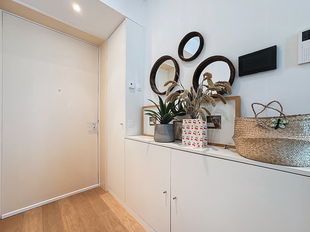 Entrée moderne avec miroirs, plantes, meubles blancs et touches naturelles pour un accueil chaleureux.