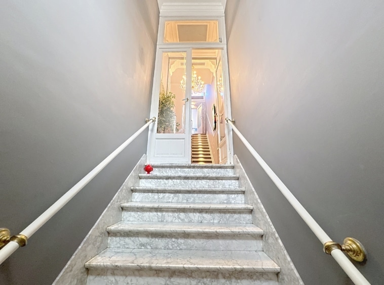 Escalier en marbre, porte vitrée lumineuse, touche verte, détail cœur rouge, ambiance élégante et accueillante.
