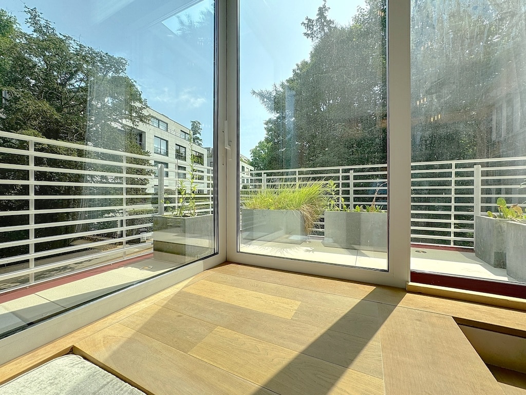Vue intérieure lumineuse avec patio moderne et verdure, bois chaleureux, ambiance calme et élégante.