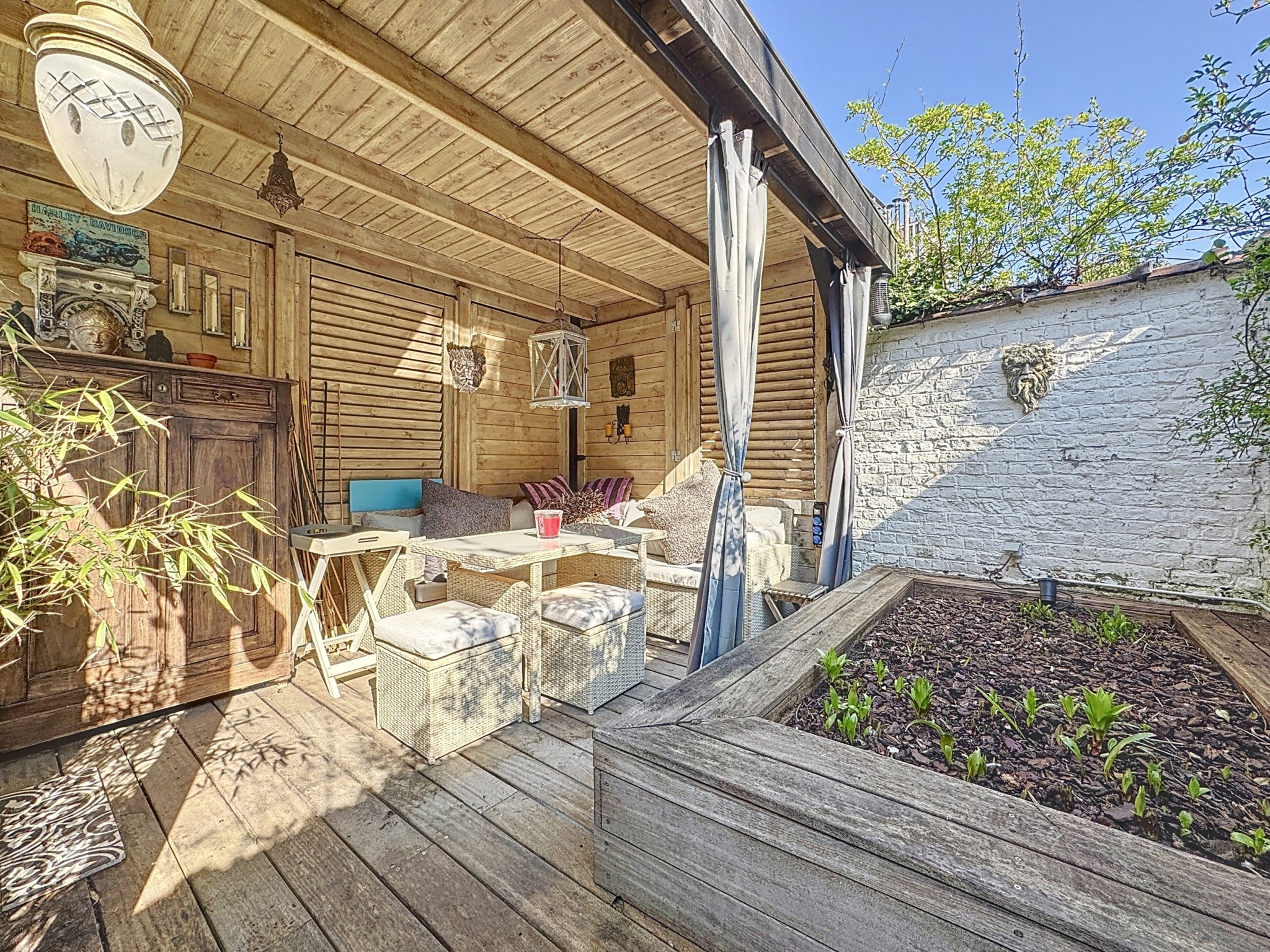 Coin extérieur cosy en bois, plantes vertes et ambiance paisible pour se détendre.
