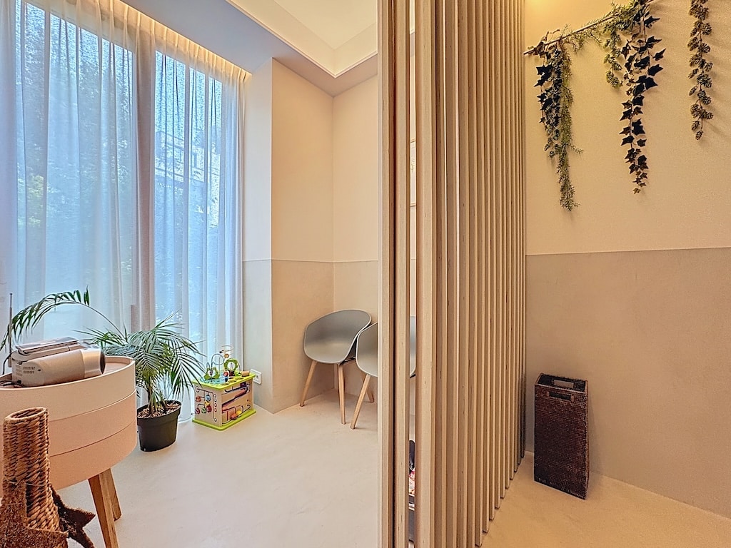 Coin détente lumineux avec plantes vertes, grandes fenêtres et mobilier minimaliste moderne.