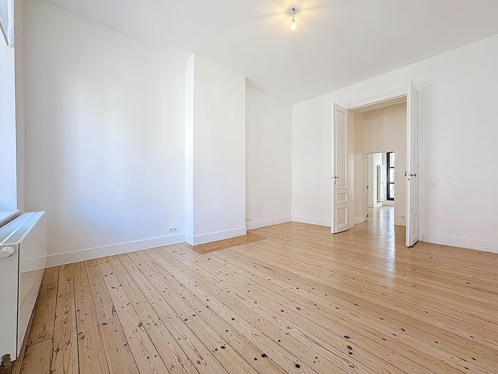 Espace lumineux et spacieux avec parquet en bois naturel et murs blancs, idéal pour personnaliser.