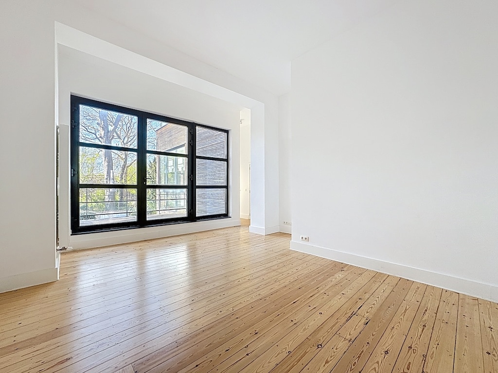 Espace lumineux avec vue sur la nature, parquet en bois, murs blancs et style minimaliste.