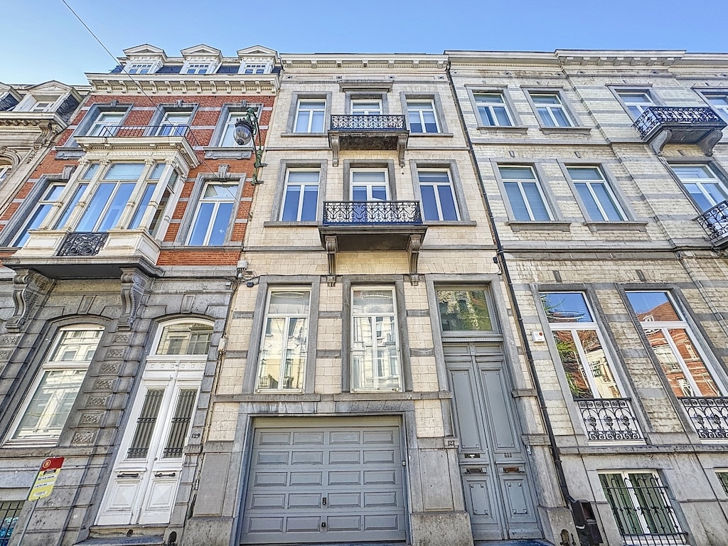 Façade dimmeuble historique avec pierre, briques, balcons en fer forgé et fenêtres variées.