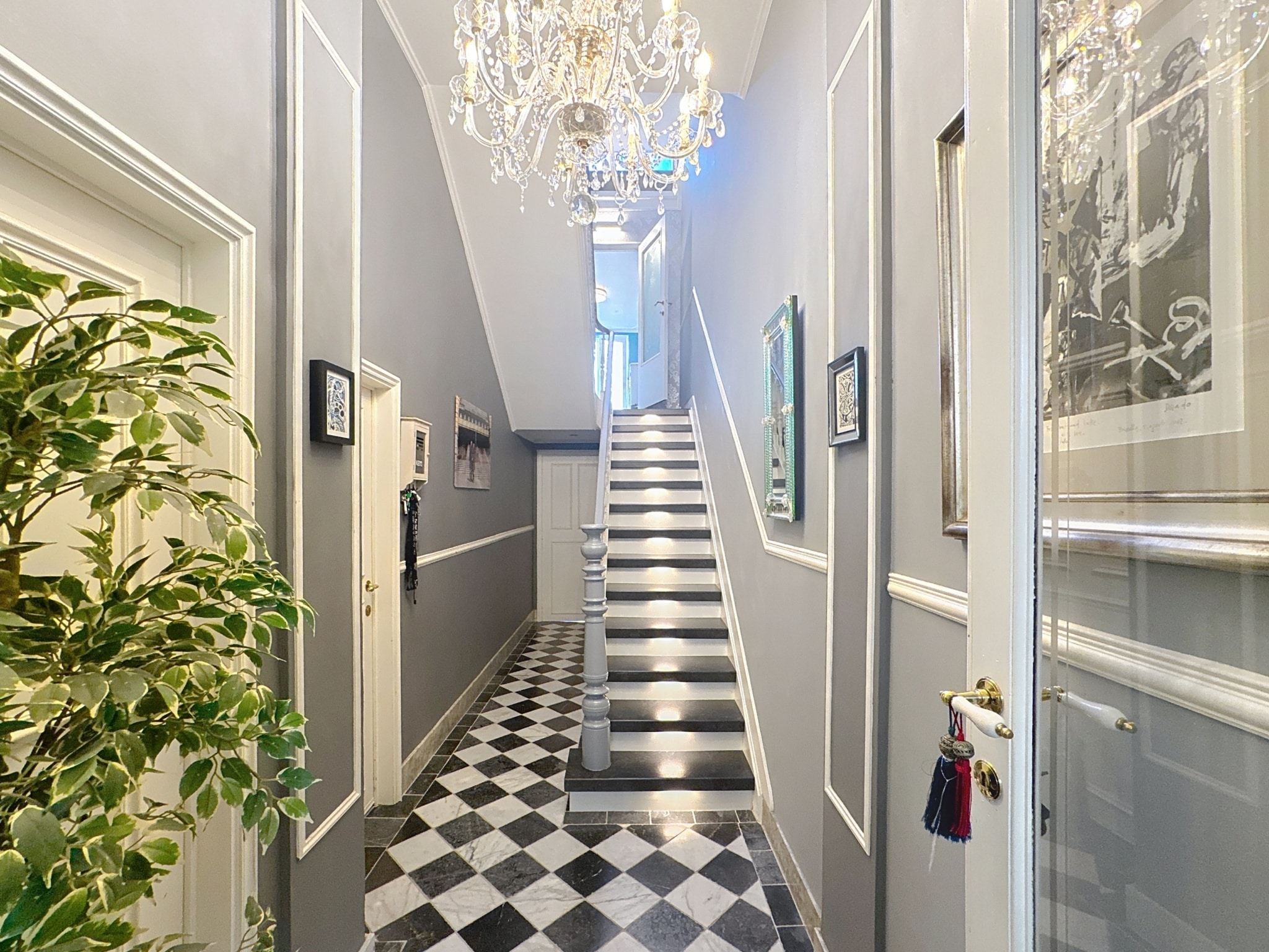 Hall d’entrée élégant avec sol en carreaux, lustre en cristal et déco sophistiquée.