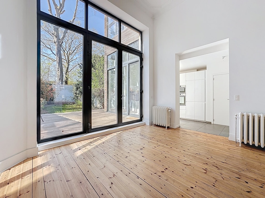 Intérieur minimaliste lumineux avec grandes fenêtres, parquet en bois naturel et vue panoramique.