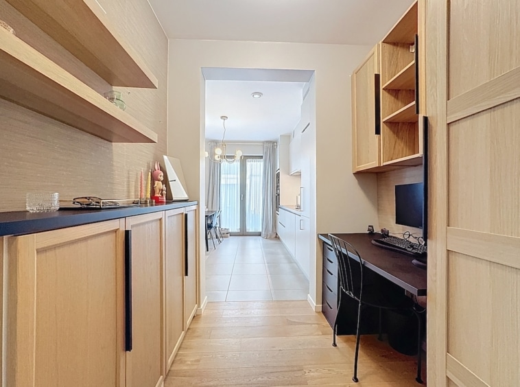 Intérieur moderne lumineux avec espace de travail, meubles en bois clair et ambiance épurée.