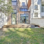 Maison contemporaine en verre avec jardin, escaliers en bois et design moderne harmonieux.