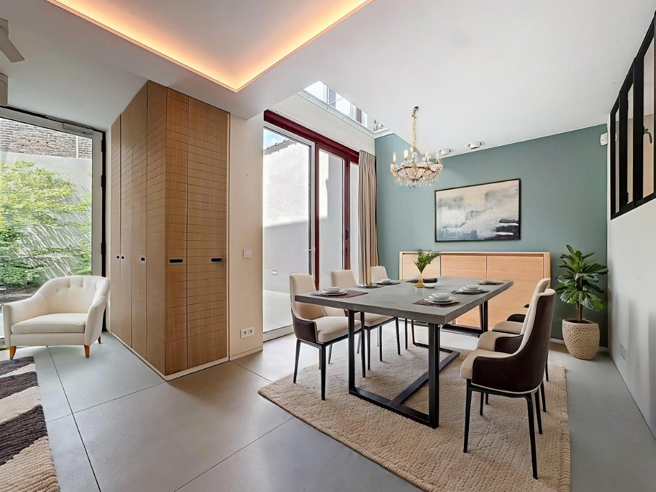 Salle à manger moderne lumineuse avec mobilier élégant, vue verte et décoration chaleureuse.