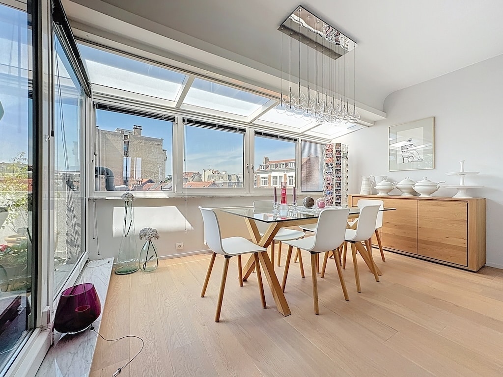 Salle à manger moderne lumineuse avec grandes fenêtres, mobilier minimaliste, vue panoramique et décoration élégante.