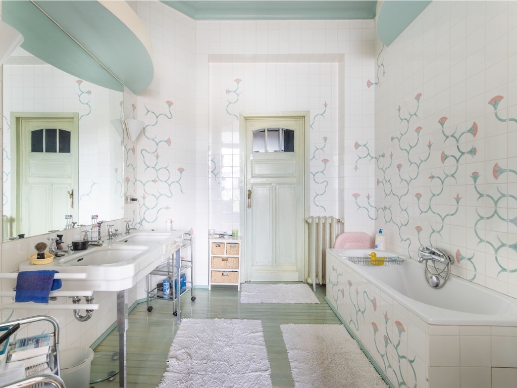 Salle de bain élégante avec double lavabo, décoration florale, baignoire et ambiance naturelle apaisante.