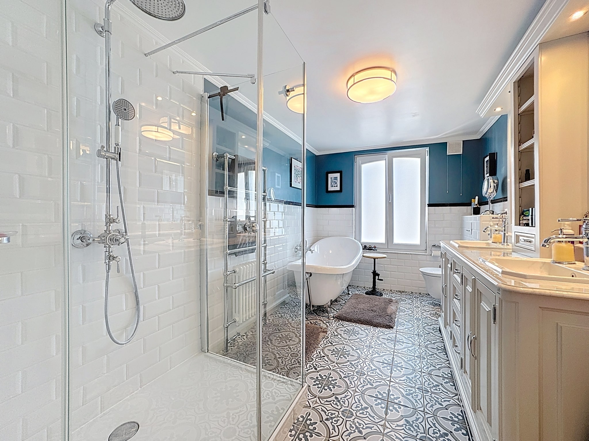 Salle de bain élégante avec baignoire îlot, douche en verre et design moderne en bleu profond.