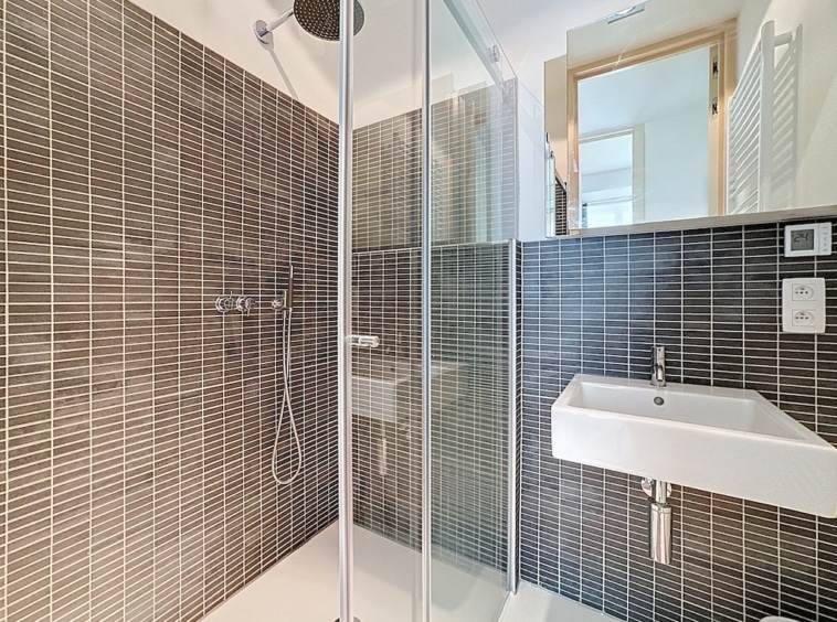 Salle de bain moderne, élégante, avec douche à l’italienne, lavabo suspendu et décoration minimaliste.