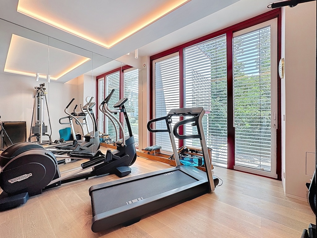 Salle de sport moderne lumineuse avec vue sur la nature, équipement high-tech et ambiance chaleureuse.