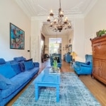 Salon cosy en bleu avec meubles élégants, œuvres d’art colorées et éclairage chaleureux.