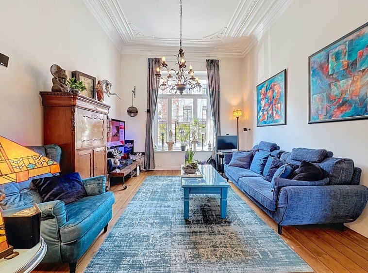 Salon moderne et cosy avec canapés bleus, œuvres colorées et ambiance chaleureuse.