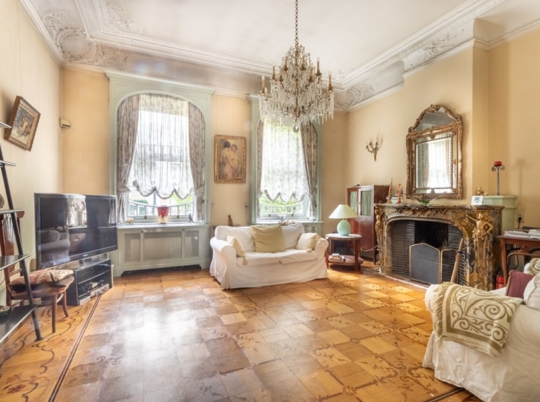 Salon élégant avec cheminée, grand miroir, sofa blanc et décoration sophistiquée.