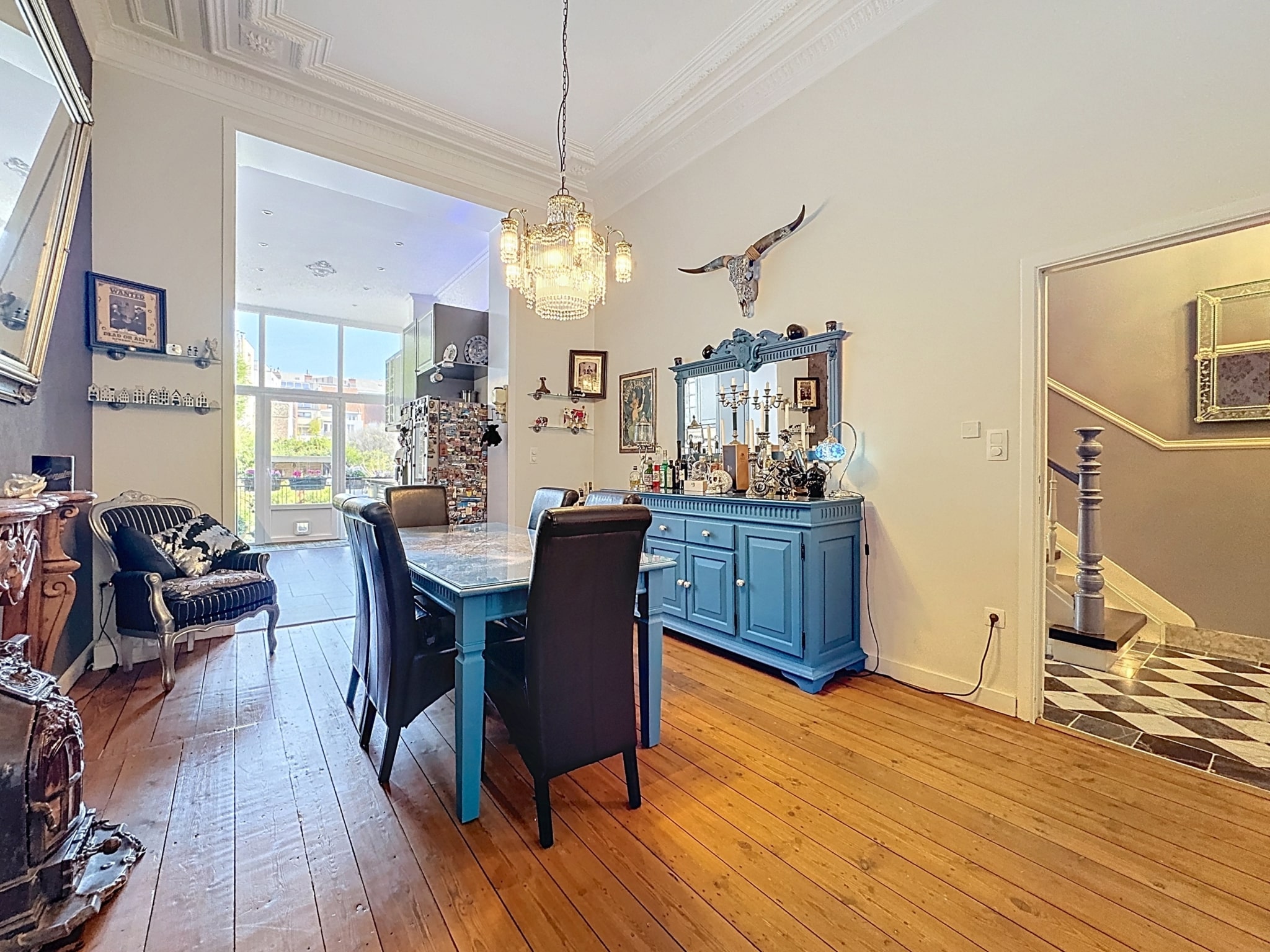 Salon et salle à manger vintage élégants, lumineux, avec mobilier bleu, parquet en bois, œuvres d’art.