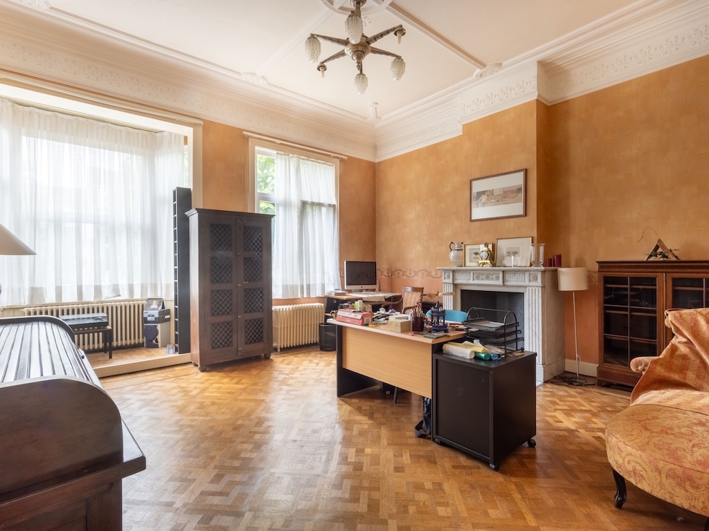 Salon lumineux avec bureau, cheminée traditionnelle, mobilier en bois et ambiance chaleureuse.