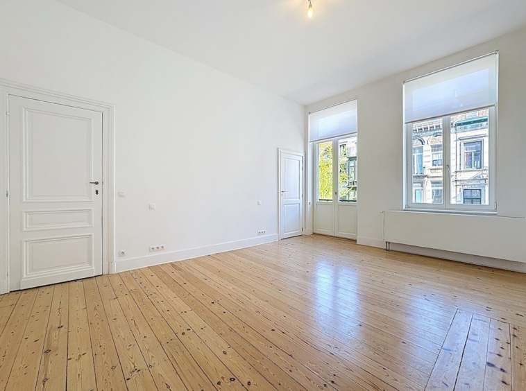 Salon lumineux avec parquet en bois clair et vue verdoyante, style minimaliste et épuré.