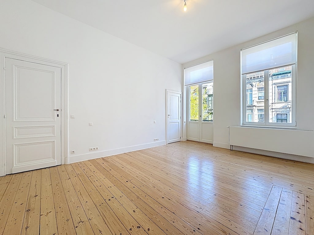 Salon lumineux avec parquet en bois clair et vue verdoyante, style minimaliste et épuré.