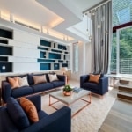 Salon moderne avec canapés bleu marine, lumière naturelle, touches de cuivre et ambiance chaleureuse.