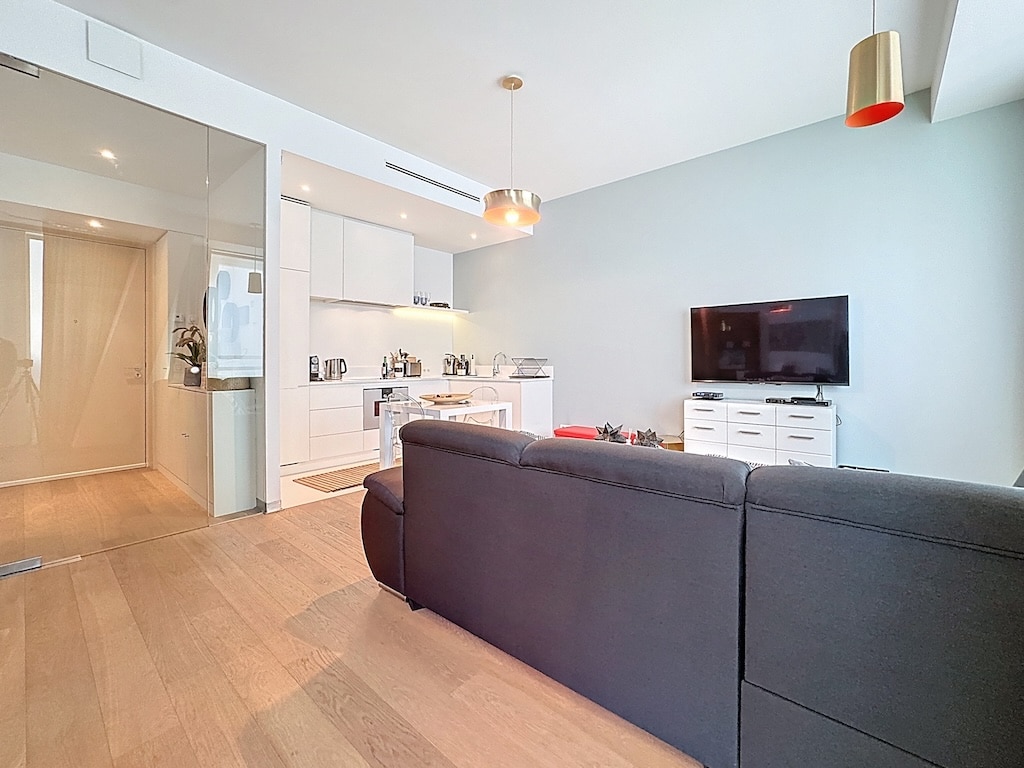 Espace de vie moderne avec cuisine ouverte, canapé noir élégant et décoration naturelle.