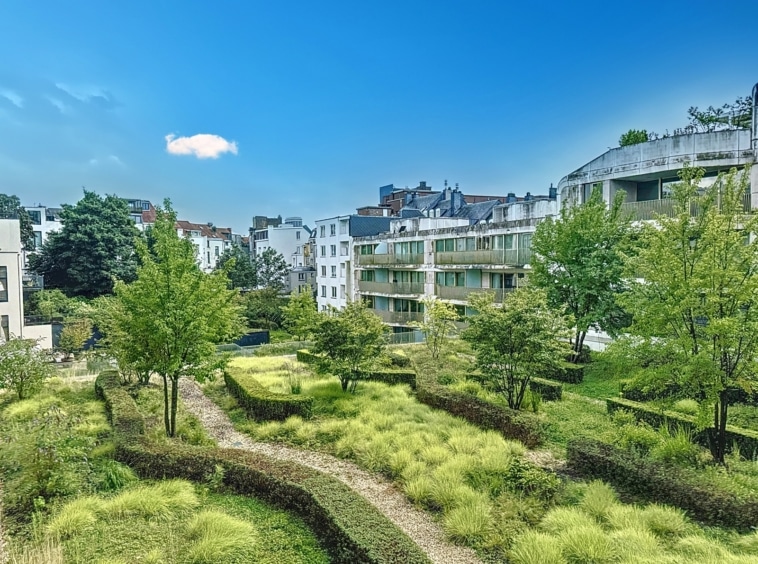 Ville moderne avec jardin verdoyant, immeubles en verre, harmonie entre architecture et nature.