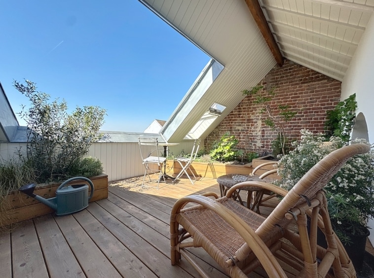 Balcon lumineux avec mobilier en rotin, plantes vertes et murs en briques pour une détente cosy.