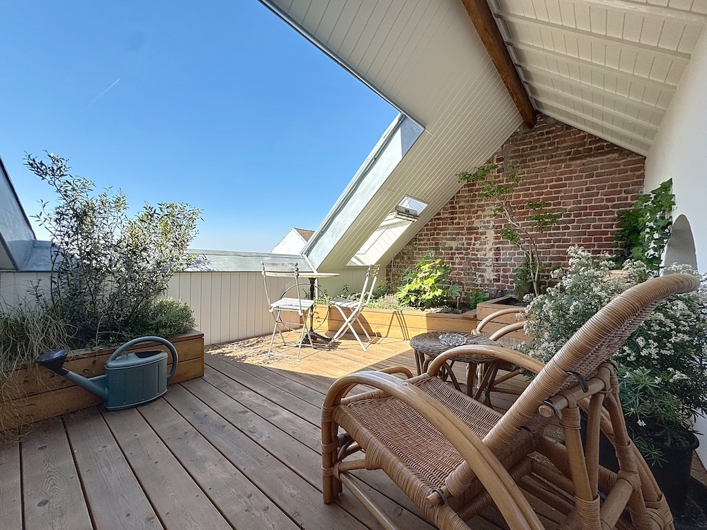 Balcon lumineux avec mobilier en rotin, plantes vertes et murs en briques pour une détente cosy.