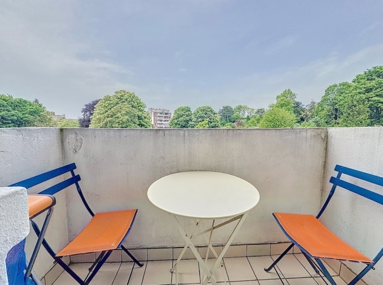 Balcon cosy avec vue verdoyante, mobilier coloré et espace parfait pour se détendre en plein air.