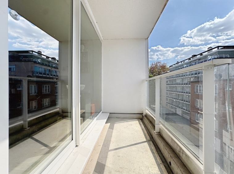 Balcon moderne en verre transparent, vue urbaine, design minimaliste, luminosité et espace relaxant.