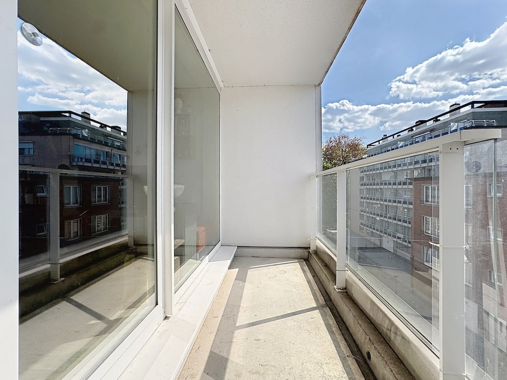 Balcon moderne en verre transparent, vue urbaine, design minimaliste, luminosité et espace relaxant.