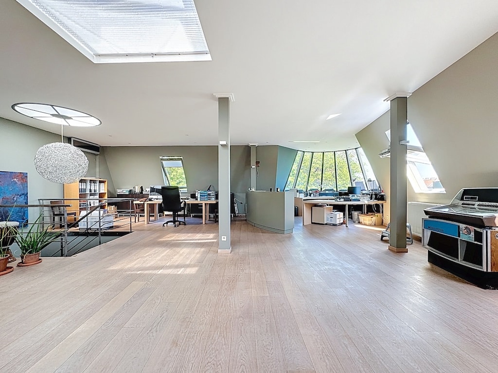Bureau moderne lumineux avec espace ouvert, grandes fenêtres, mobilier ergonomique et espace détente.