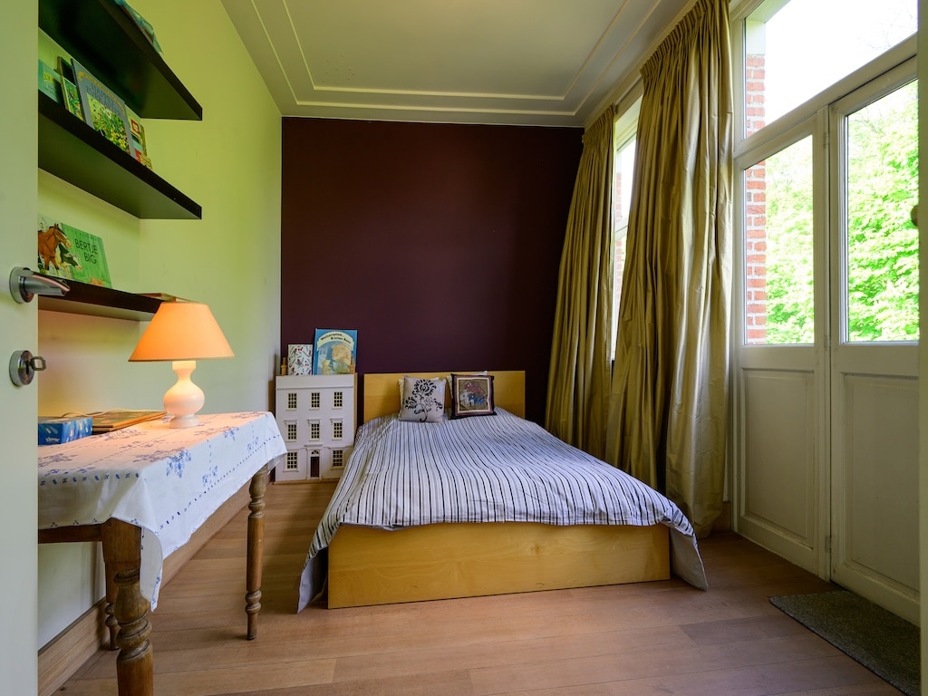 Chambre cosy avec lit en bois, lumière naturelle, murs colorés, décoration élégante, espace de détente.
