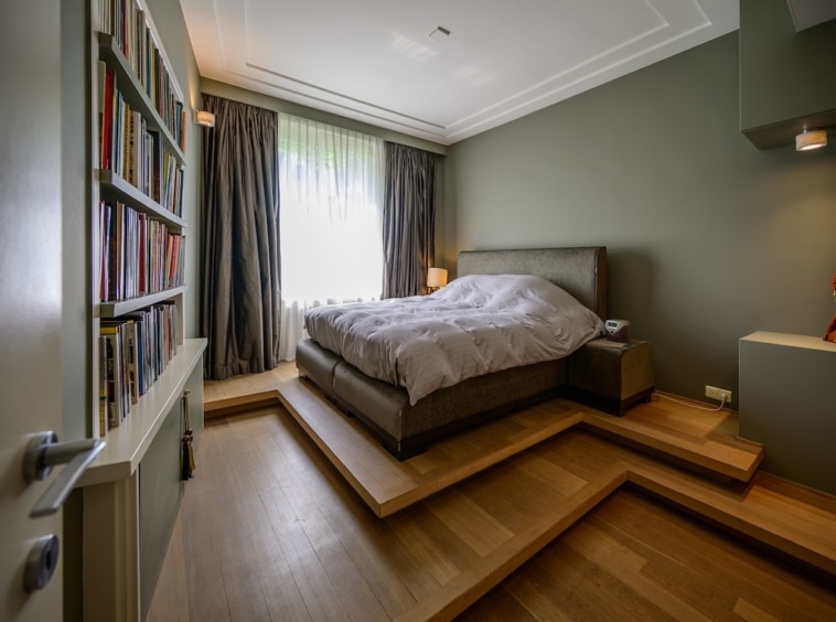 Chambre moderne avec lit king, lumière naturelle, décoration épurée et bibliothèque chaleureuse.
