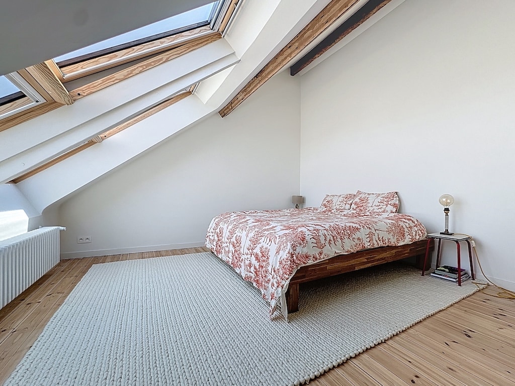Chambre cosy et lumineuse avec lits, bois clair, accents métalliques et ambiance relaxante.