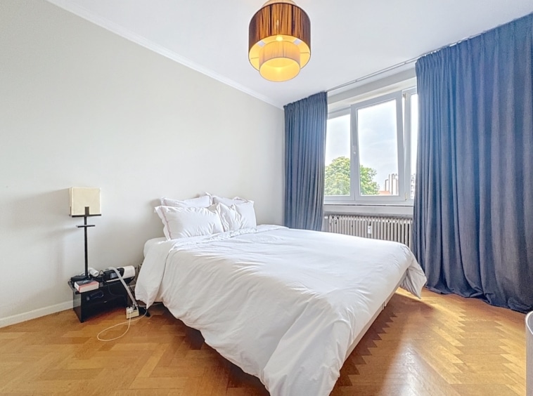 Chambre moderne et cosy avec parquet en chevrons, lumière naturelle et décoration épurée en blanc et bleu.