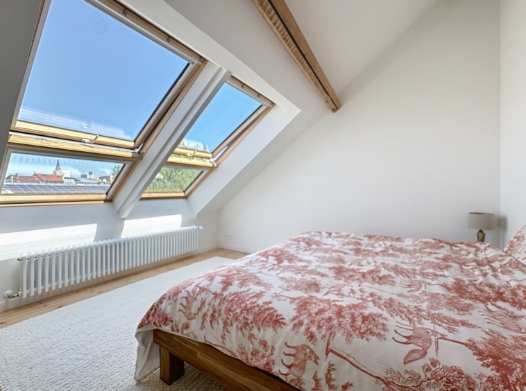 Chambre lumineuse en loft avec fenêtres en baie, décoration florale, style moderne et apaisant.