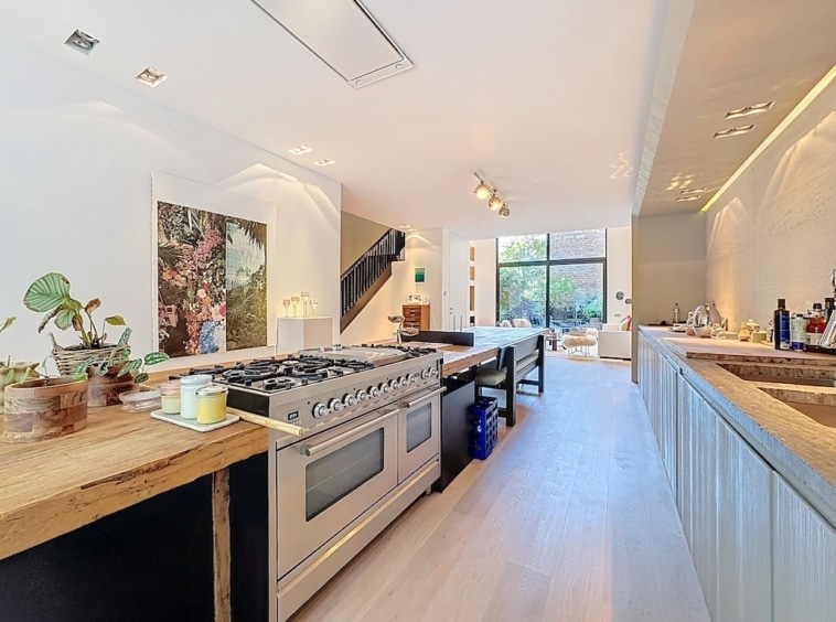 Cuisine moderne lumineuse avec îlot en bois, équipements design, grande luminosité et décoration élégante.