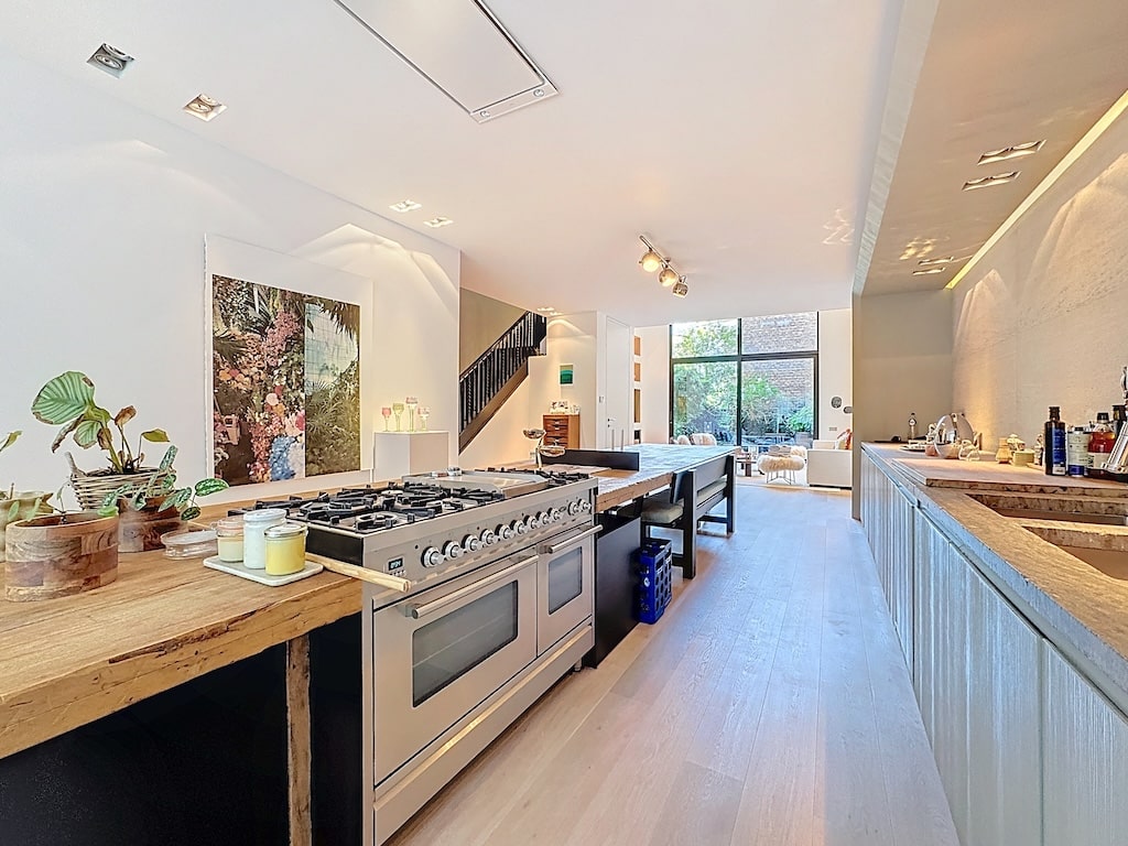 Cuisine moderne lumineuse avec îlot en bois, équipements design, grande luminosité et décoration élégante.