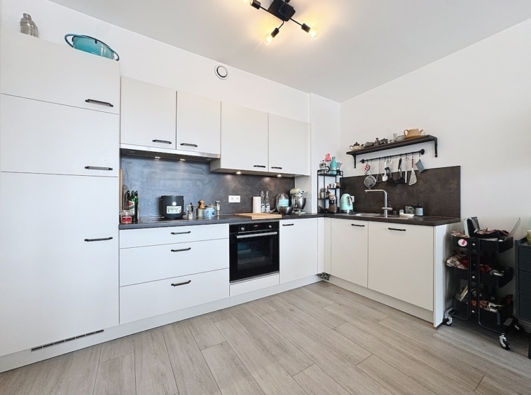 Cuisine moderne blanche, éclairee, équipée, avec plan de travail organisé, sol en bois clair.