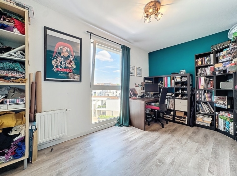 Espace créatif lumineux avec bureau, étagères colorées et mur turquoise, idéal pour travailler et sinspirer.