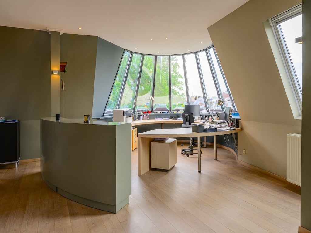 Bureau moderne avec murs courbes, grandes fenêtres lumineuses et espace collaboratif élégant.
