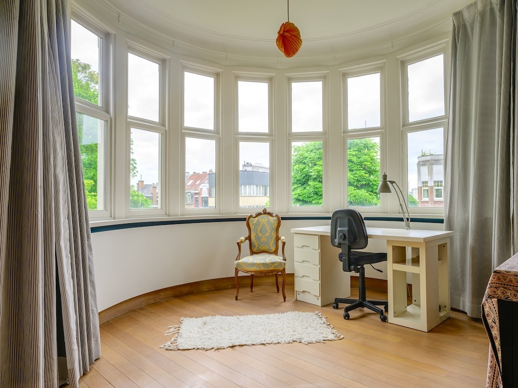 Salon lumineux avec vue verdoyante, mobilier élégant mixant style traditionnel et moderne.