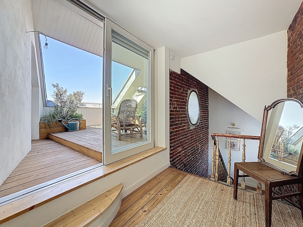 Intérieur moderne et lumineux avec terrasse en bois, mur en briques apparentes, ambiance cozy et naturelle.