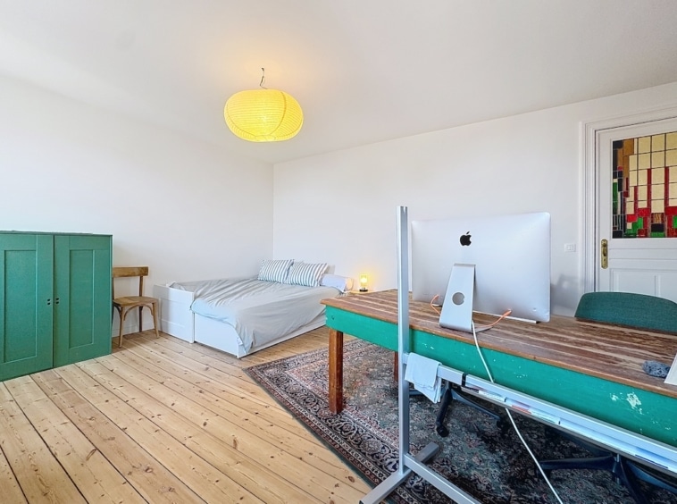 Intérieur lumineux avec meubles colorés, grand vitrail, espace de travail convivial et ambiance chaleureuse.