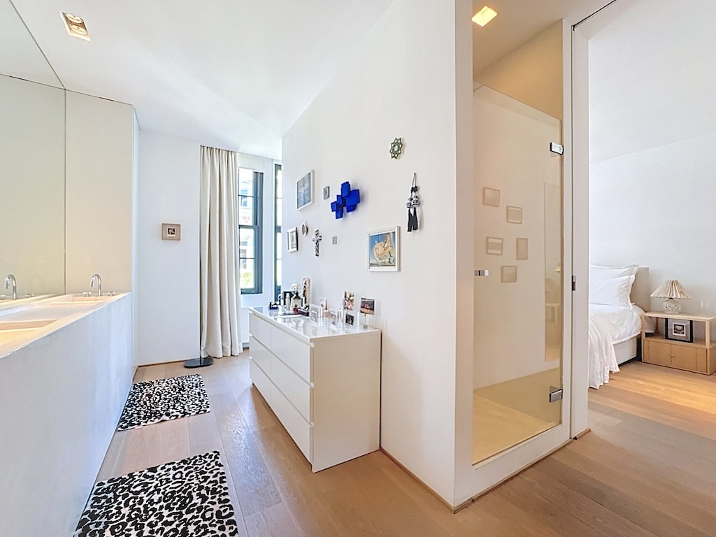 Chambre moderne avec salle de bain ouverte, design épuré, lumineux et élégant en blanc et bois clair.