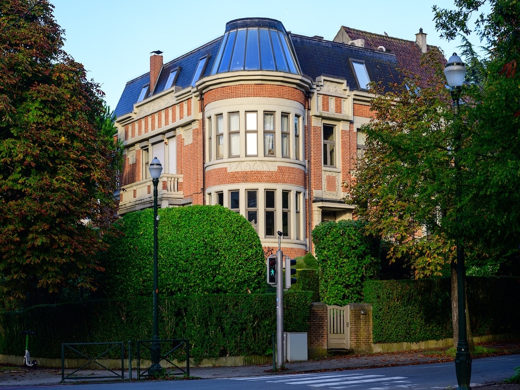 Manoir moderne avec toit en verre, façade en brique et jardin élégant, harmonie entre style classique et contemporain.