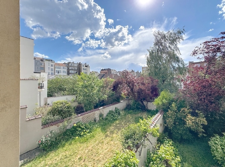Jardin urbain paisible avec nature luxuriant et bâtiments modernes sous un ciel bleu.